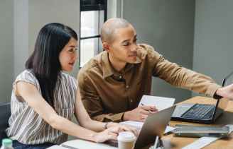 man and woman looking at laptop computers